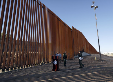 Border Patrol agents and others stand next to a new stretch of border wall in Calexico, California
