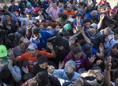 Central American migrants, part of the caravan hoping to reach the US border, pray at a temporary shelter in Tijuana, Mexico