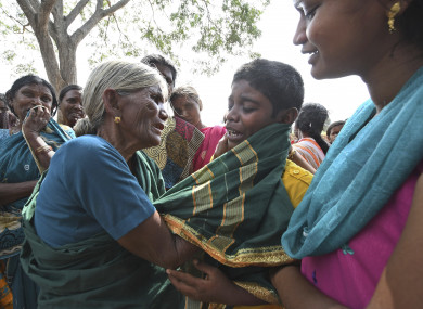 A boy cries consoled by his grandmother after his mother died of suspected food poisoning.