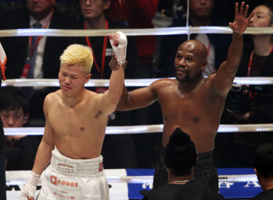 Floyd Mayweather holds up Tenshin Nasukawa's hand after their New Year's Eve bout in Tokyo.
