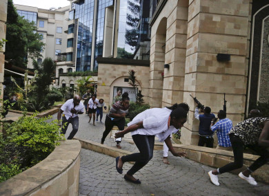 Civilians flee as security forces aim their weapons at the buildings of a hotel complex in Nairobi, Kenya, yesterday.