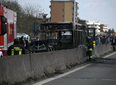 Firefighters stand by the gutted remains of the bus in San Donato Milanese, near Milan.