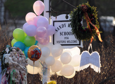 2012 file photo, flowers, teddy bears, candles, balloons and a pair of angel wings left by mourners are seen at the Sandy Hook Elementary School sign