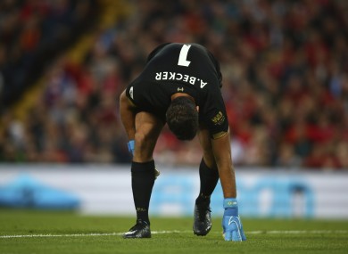 Liverpool's goalkeeper Alisson Becker holds his leg.