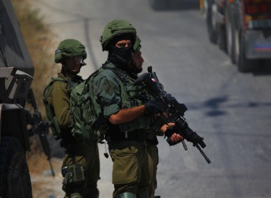Israeli soldiers stand guard near the scene in the settlement of Migdal Oz.