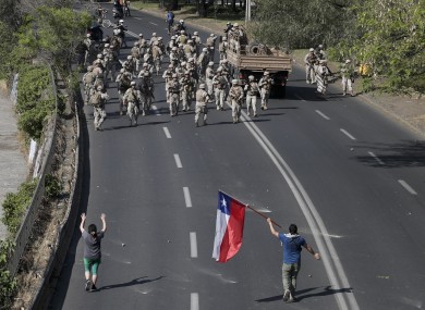 Demonstrators challenge soldiers as a state of emergency remains in effect in Santiago, Chile.