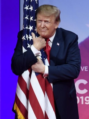 President Donald Trump hugs the American flag at the Conservative Political Action Conference.