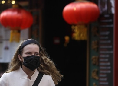 A woman wears a mask as she walks near China Town in London.