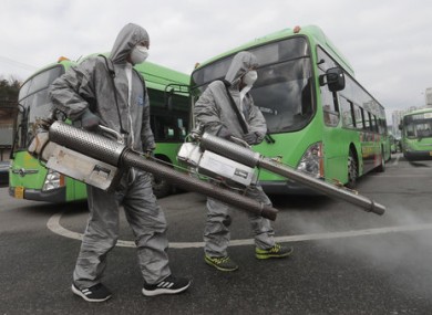 Workers wearing protective suits spray disinfectant in Seoul, South Korea.