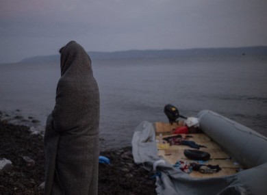 A migrant sits wrapped in blankets on the beach of the village of Skala Sikamias after crossing the Aegean Sea from Turkey in a dinghy.