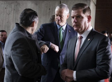 Massachusetts Governer Charlie Baker, centre, bumps elbows with Aaron Michlewitz Mayor Marty Walsh.