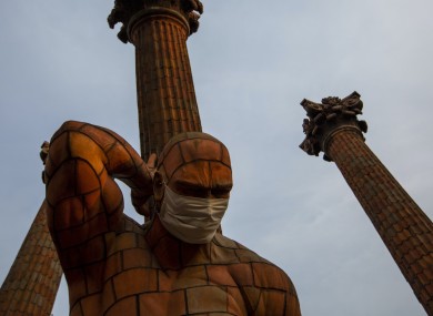 A medical mask covers the face of a statue in Guatemala City.