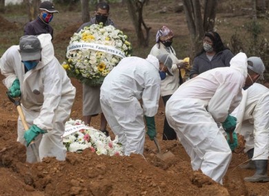 Relatives watch cemetery workers shovel dirt over the coffin of a man who died of Covid-19