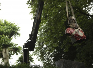 A bust of Belgium's King Leopold II is hoisted off of its plinth by a crane as it's removed from a park in Ghent.