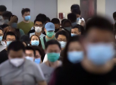 Commuters wear face masks as they walk through a subway station in Beijing today.