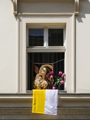 A portrait of Virgin Mary with flowers and a Vatican flag seen on a window during the annual Corpus Christ Procession in Krakow.