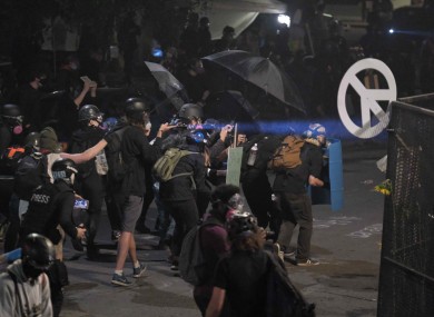 Protesters take cover as federal officers fire crowd control munitions to clear the area after protesters gathered in front of the federal courthouse in Portland