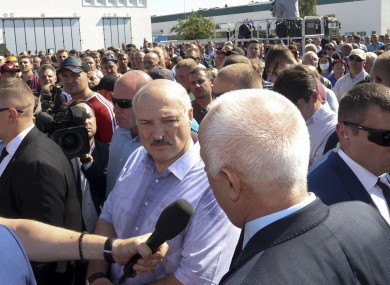 Belarusian President Alexander Lukashenko, center, surrounded by his bodyguards listens to an employee of the Minsk Wheel Tractor Plant