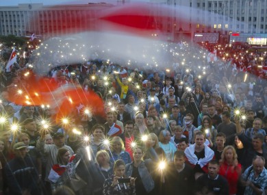 Belarusian opposition supporters light phones lights and wave an old Belarusian national flags during a protest rally in front of the government building at Independent Square in Minsk, Belarus