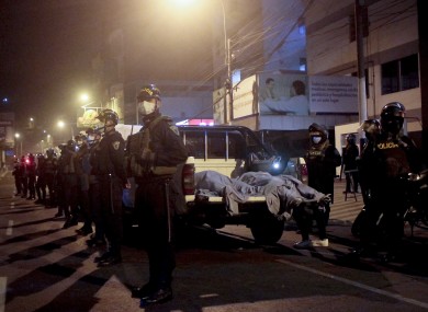 Police officers stand guard near two bodies outside of a disco in Lima, Peru