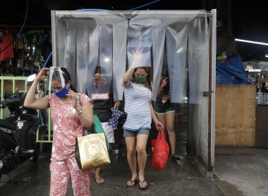 Women exit from a disinfecting area after buying food at a public market in Quezon City in the Philippines.