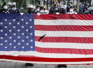 A giant American flag is unfurled as the national anthem is plated at the National September 11 Memorial and Museum.