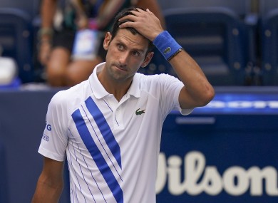 Novak Djokovic, of Serbia, reacts after inadvertently hitting a line judge with a ball.