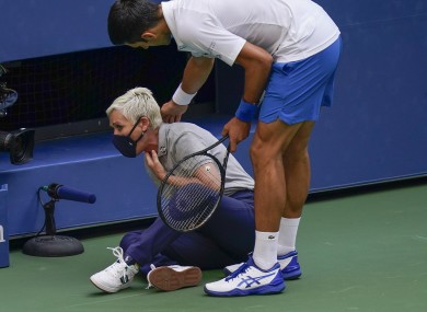 Novak Djokovic, of Serbia, checks a female official after hitting her with a ball.