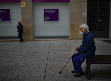 An elderly man sits on a bench wearing a face mask in Pamplona, northern Spain