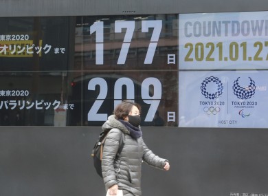 A pedestrian walks by a clock counting down to the Olympics and Paralympics in Tokyo.