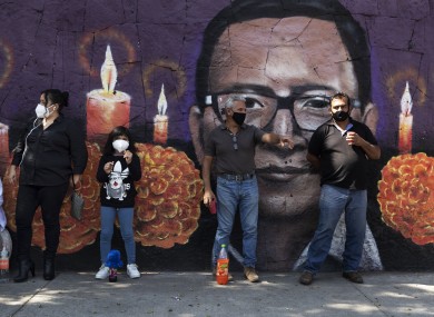 People wait in front of a mural outside the San Nicolas Tolentino cemetery in the Iztapalapa district of Mexico City.