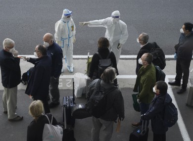 A worker in protective coverings directs members of the WHO team on their arrival at the airport in Wuhan.