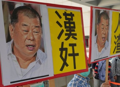 Pro-China supporters hold the pictures of Jimmy Lai with words