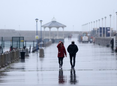 File photo - People walking in heavy rain along Dun Laoghaire Pier