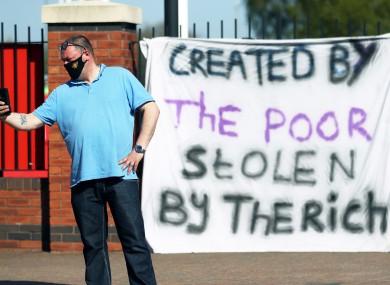 A fan stands outside Old Trafford in response to the news of a proposed Super League.