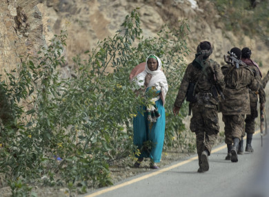 A woman walks past Ethiopian government soldiers by the side of a road north of Mekele, in the Tigray region of northern Ethiopia