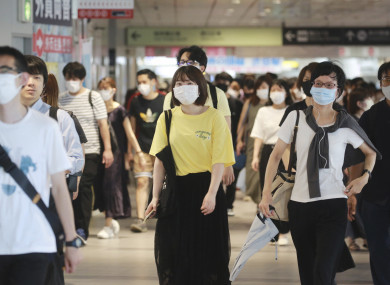 People wearing face masks to protect against the spread of the coronavirus walk at train station in Tokyo.