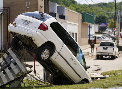 A car leans against a utility pole after being upended by floods.