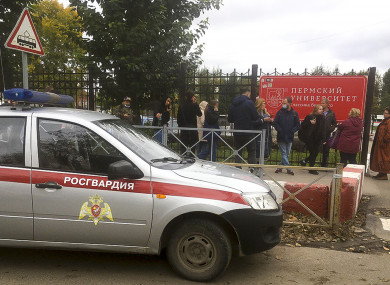 People stand behind the fence near the Perm State University with the a Posguardia.