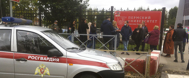 People stand behind the fence near the Perm State University with the a Posguardia.