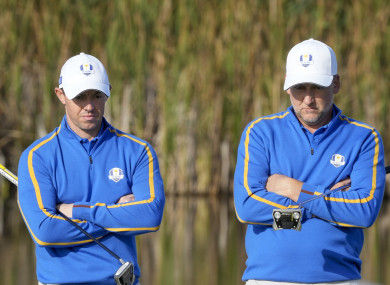 Team Europe's Rory McIlroy and Ian Poulter wait to putt.