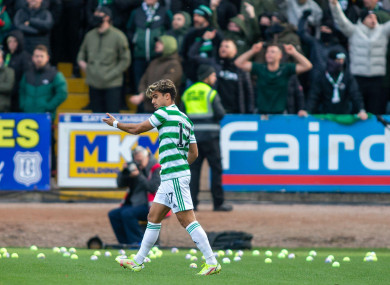 Joao Pedro Neves Filipe Jota of Celtic attempts to clear the pitch of tennis balls thrown on in protest.