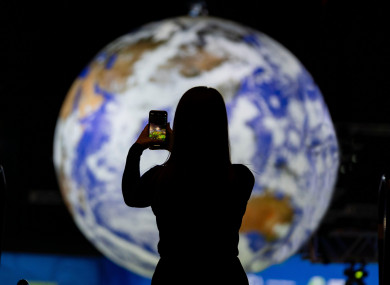 A delegate takes photo standing in front of large globe inside the Action Zone at COP26 yesterday.