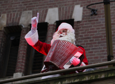 A man wearing a Santa Claus costume plays the accordion on a balcony of a closed shop at the Dam Square in Amsterdam yesterday.