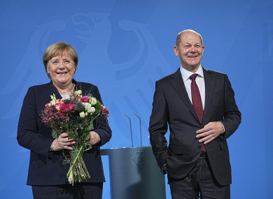 Chancellor Olaf Scholz hands over a bouquet of flowers during the handover of office from former Chancellor Angela Merkel.