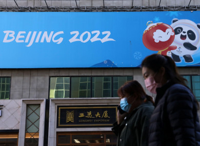 People walk past a banner with a sign of Beijing 2022 Winter Olympic Games.