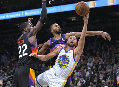 Golden State Warriors guard Stephen Curry shoots between Phoenix Suns center Deandre Ayton and guard Cameron Payne.