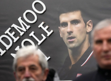 Supporters hold up a picture of Djokovic, reading: