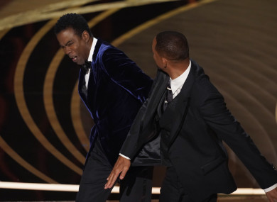 Will Smith, right, hits presenter Chris Rock on stage while presenting the award for best documentary feature at the Oscars