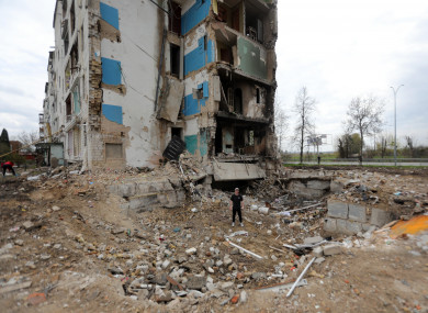 A man stands in a crater of a Russian shell that brought down a section of an apartment building in Borodianka.